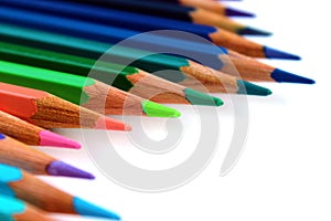 Bright color pencils diagonal wave on white background with green pencil on focus