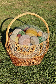 Bright, colored, beautiful balls of yarn for knitting spokes In a wicker basket.