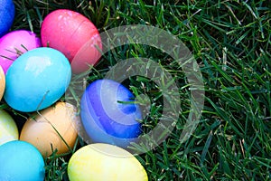 Bright colored Easter eggs piled in the green grass.