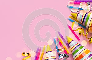 Bright colored party hats and and holiday candles on a pink background. Holidays concept. Top view. Place for text