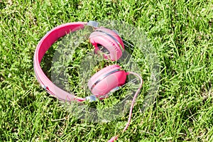 Bright colored pink headphones on green sward