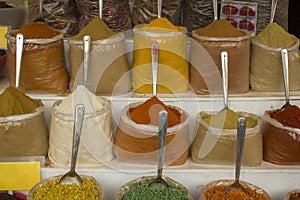 Bright colored powders and dried spices in bags with spoons on the counter