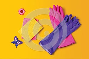 Bright colored rubber gloves and cleaning sponges on a yellow background. Household chores or house cleaning services. Cleaning