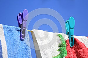 Bright colored towels pegged to a washing line against a clear blue sky