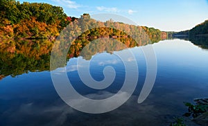 Bright colorful autumn forest landscape, trees near river and blue sky