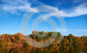 Bright colorful autumn forest landscape, trees near river and blue sky