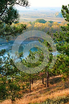 Bright colorful autumn forest landscape, trees near river and blue sky, view from high hill