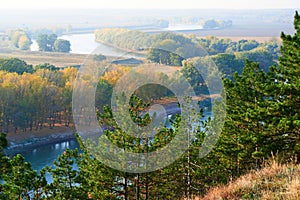 Bright colorful autumn forest landscape, trees near river and blue sky, view from high hill