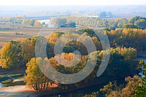 Bright colorful autumn forest landscape, trees near river and blue sky, view from high hill