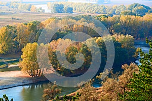 Bright colorful autumn forest landscape, trees near river and blue sky, view from high hill