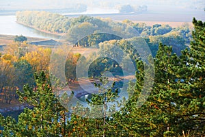 Bright colorful autumn forest landscape, trees near river and blue sky, view from high hill