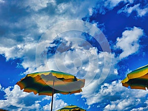 Bright colorful beach umbrella on sunny blue sky day. Multicolored beach umbrella under blue sky on sunny cloudless day. Summer