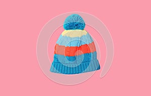 Bright colorful blue baby knitted winter hat isolated on pink background