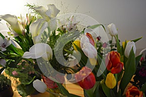 Beautiful bouquets in jars, glass glasses, bottles placed on a yellow wooden table.