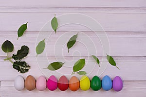 Bright, colorful easter eggs in a row, on a wooden white background