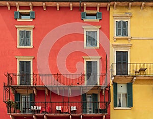 Bright colorful facade of old European building with windows, balconies, tables and chairs and flowers in Verona, Italy
