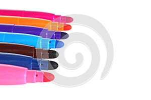 Bright colorful multicolored markers lie on a white background.