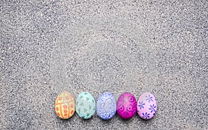 Bright, colorful painted eggs for Easter, laid out in a row border place for text granit rustic background top view close up