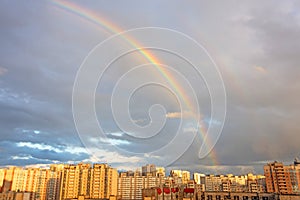 Bright colorful rainbow over, sun shining in rainy day, beautiful colors phenomenon sky weather, multi-storey residential