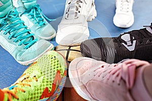 Bright and colorful sport shoes circle with basket ball top view. Set of different sneakers on blue floor, copy space