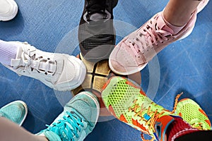 Bright and colorful sport shoes circle with basket ball top view. Set of different sneakers on blue floor, copy space