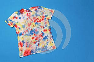 A bright colorful tie dye T-shirt on a blue background