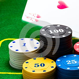 Bright columns of poker chips behind which falls a pair of aces