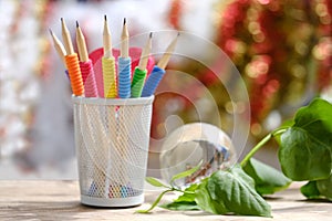 bright composition on wooden table with blue, yellow, red colored pencils with lead, glass ball globe, green plant branch writing