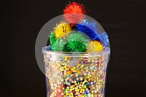 A bright container full of colourful, fluffy pom poms