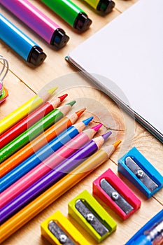 Bright crayons, markers and sharpeners along with a notebook on the table