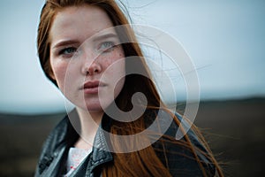 A bright, defiant woman with long red hair looks up proudly.