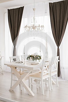 Bright dining set: a table with chairs in the bright living room is opposite the window, above the table hangs