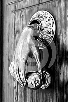 Bright doorknocker with hand shape on old wooden door