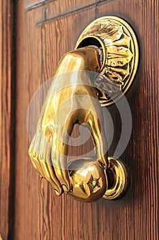 Bright doorknocker with hand shape on old wooden door