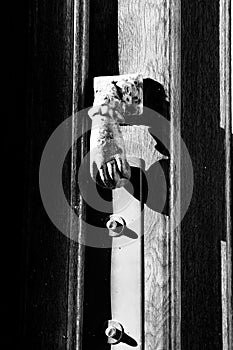 Bright doorknocker with hand shape on old wooden door