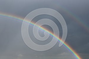 Bright double rainbow with dark rain clouds in the nature background