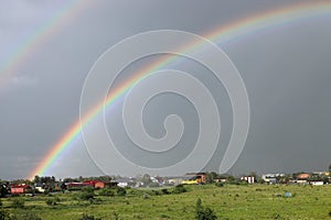 Bright double rainbow with dark rain clouds in the nature background