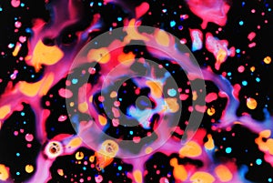 Bright drops of paint pink, orange, blue on a black background. Abstraction. Art image