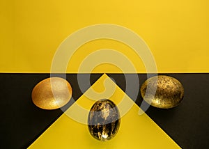Bright Easter. Eggs are black and gold on the background of a geometric pattern.