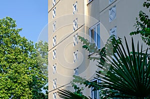 Bright facade of an apartment building surrounded by palm