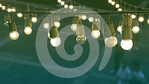 Bright festival garland light bulbs hanging over outdoor shopping area copy space