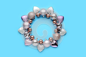 Bright festive wreath made of beautiful Christmas balls on light blue background, top view. Space for text