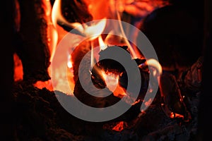 A bright fire of high temperature from natural firewood and branches burns in stove and heats house during cold season, background