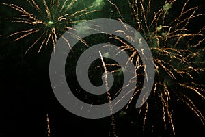 Bright fireworks with a green glowing center with green sparks and smoke, against the background of the night sky