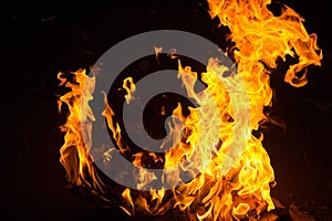Bright flames of fire on a dark background close up
