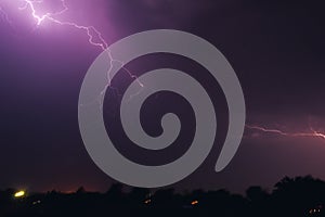 Bright flash of lightning illuminated the night sky and dyed clouds in a blue violet color
