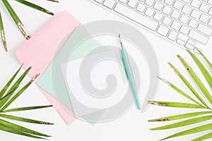 Bright flat lay fashion mock up: white keyboard, golden palm leaves, colorful cards, envelope and dip pen on white background