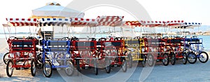 Bright four-wheeled bicycles with striped cloth roofs