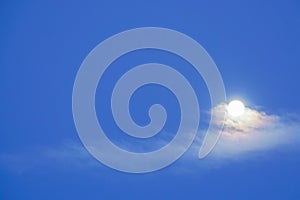 Bright full moon with clouds in deep blue sky