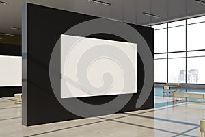 Bright gallery interior with empty white mock up banner on black wall installation, windows with city view and daylight. Museum